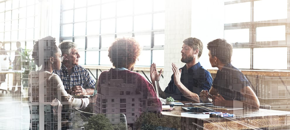 Multiple exposure shot of businesspeople having a meeting superimposed over a cityscape