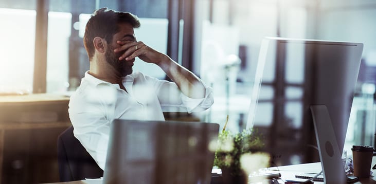 Cropped shot of a young businessman looking stressed while working late in the office