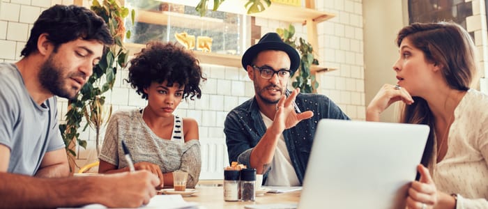 Portrait of creative business team sitting at a coffee shop with laptop. Young man discussing new business ideas with colleagues at a cafe.