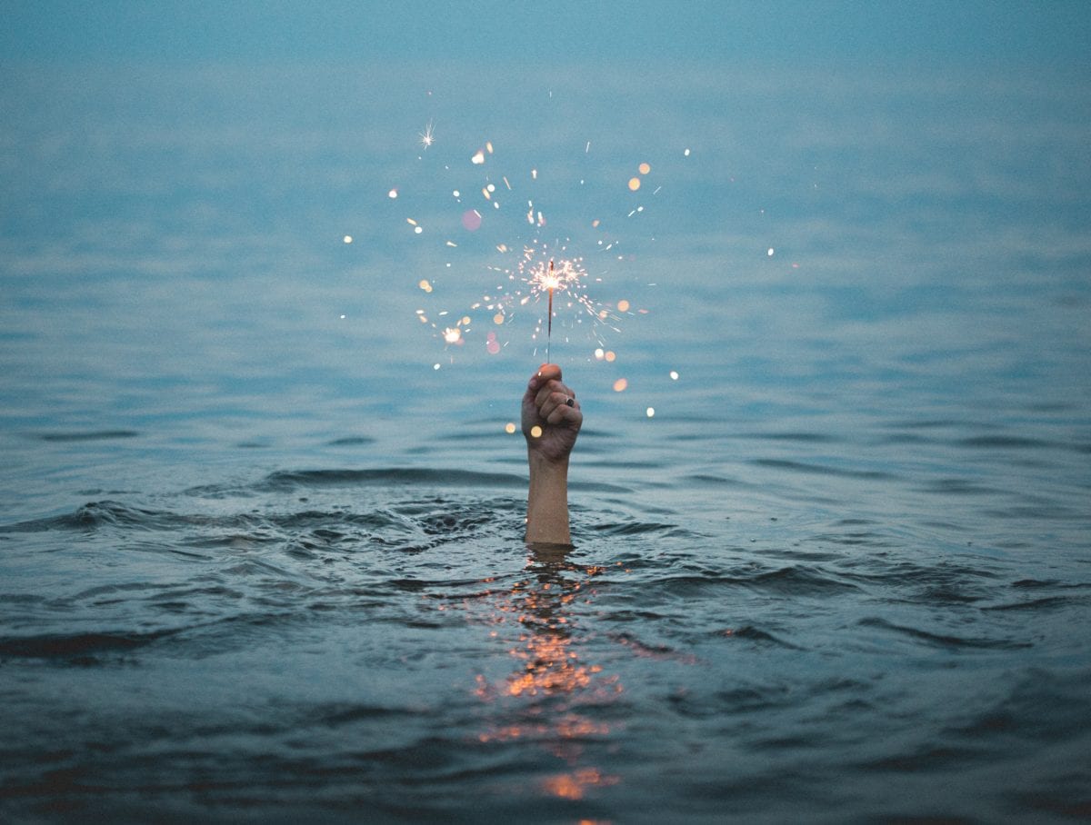 Person holding hand above water with sparkler