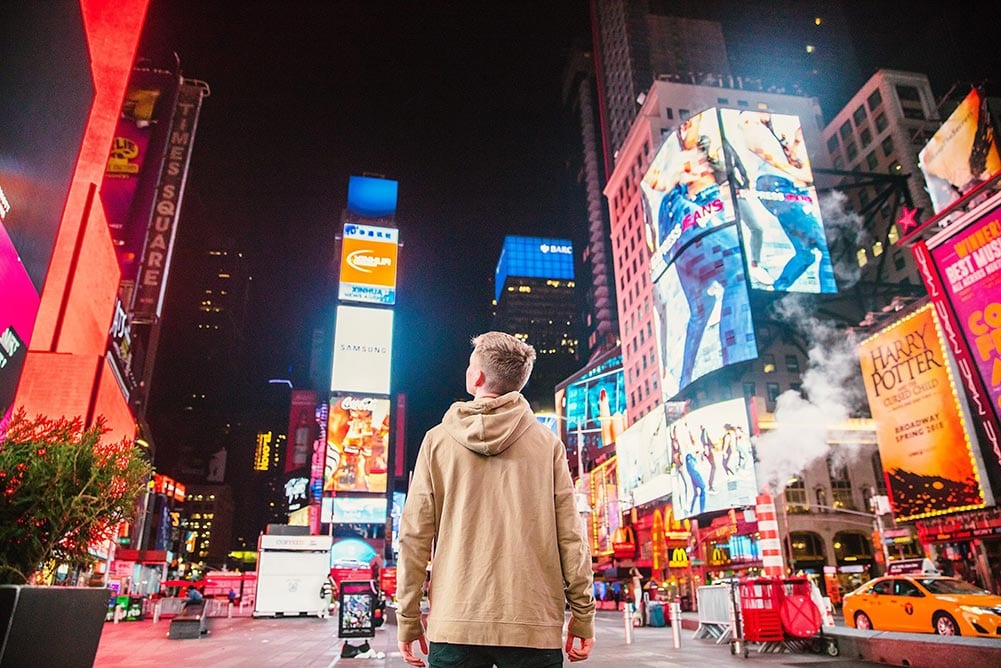 Young man standing in the middle of New York City at night