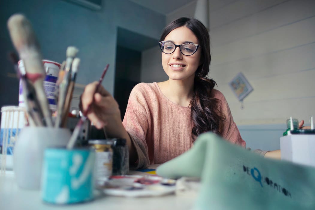 A talented artist dips her paintbrush in a new shade of blue paint.